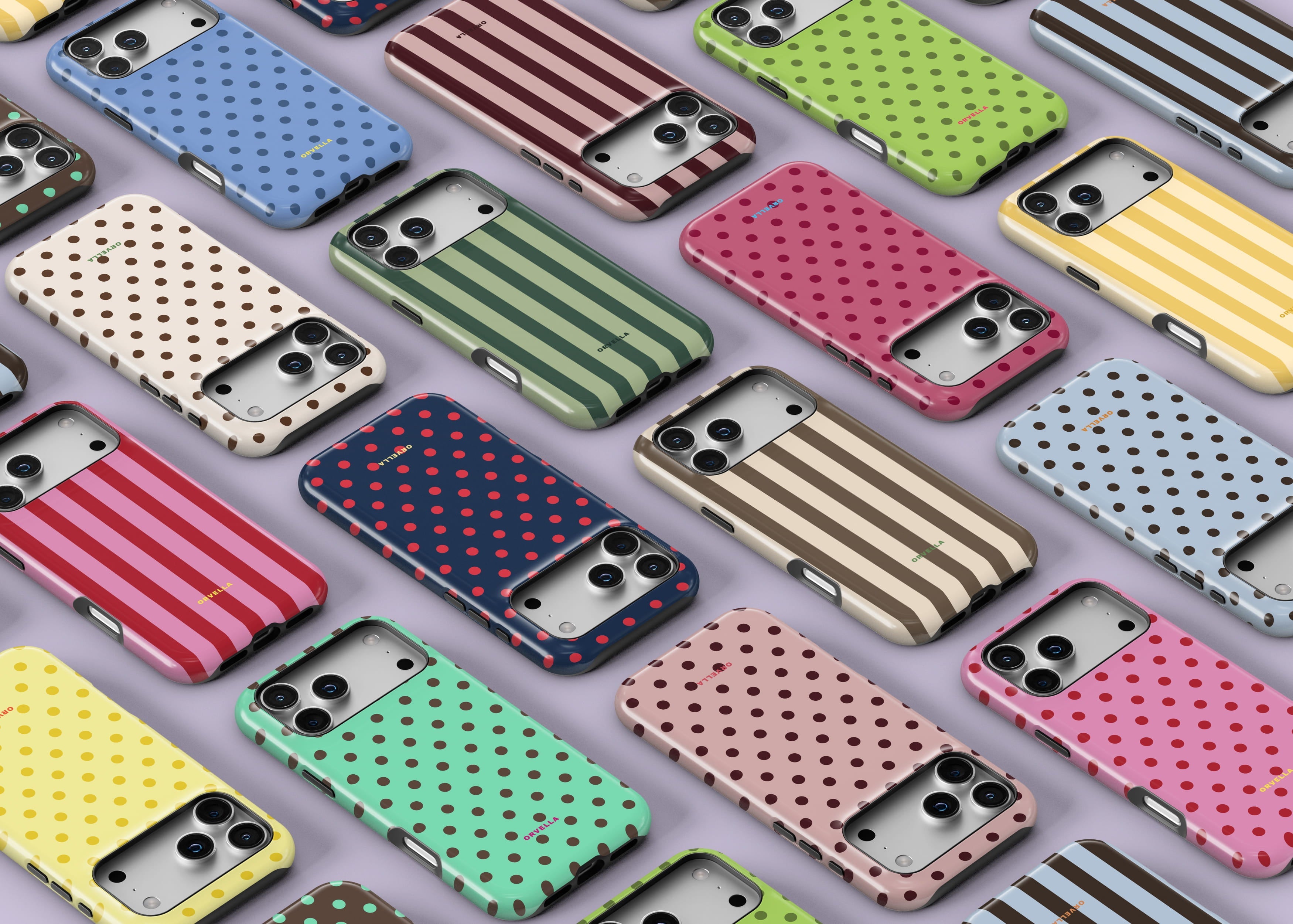 Flat lay of assorted patterned phone cases arranged diagonally on a light background, featuring pink, red, purple and blue designs including stripes, swirls, cherries, strawberries, florals, hearts, Mediterranean icons and graphic text prints.