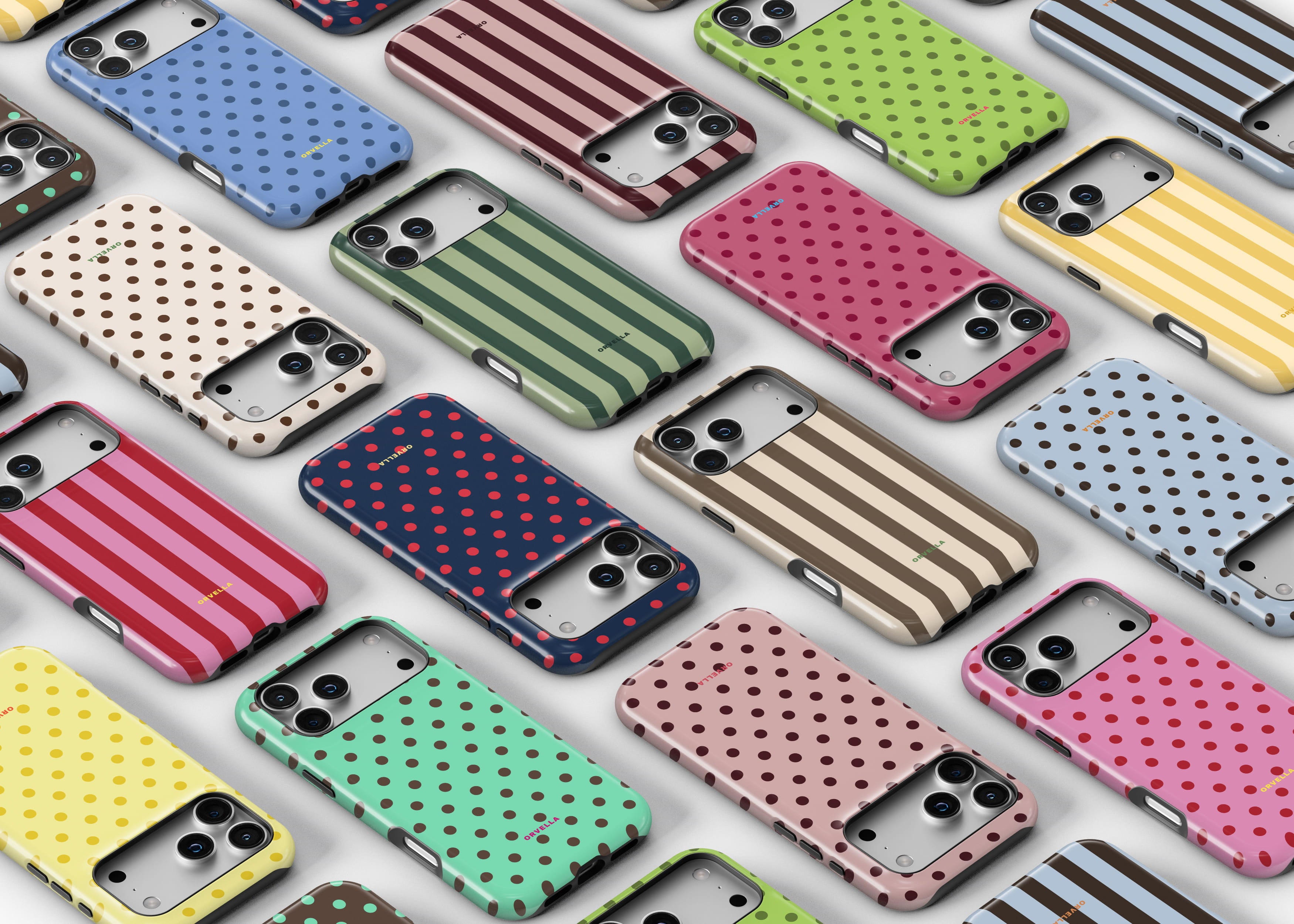 Colourful patterned phone cases arranged in a neat flat lay on a light background, featuring polka dots and stripes in red, blue, green, yellow, and neutral tones, showcasing a playful, stylish collection of designs. Phone case designs for iPhone and Samsung devices.